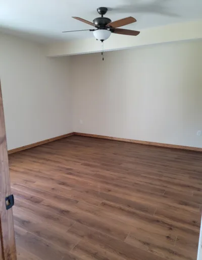 An empty room with hardwood floors and a ceiling fan.